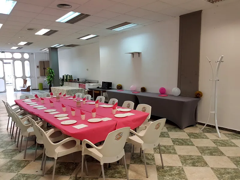 Mesa larga con mantel rosa y sillas blancas preparada para una celebración familiar