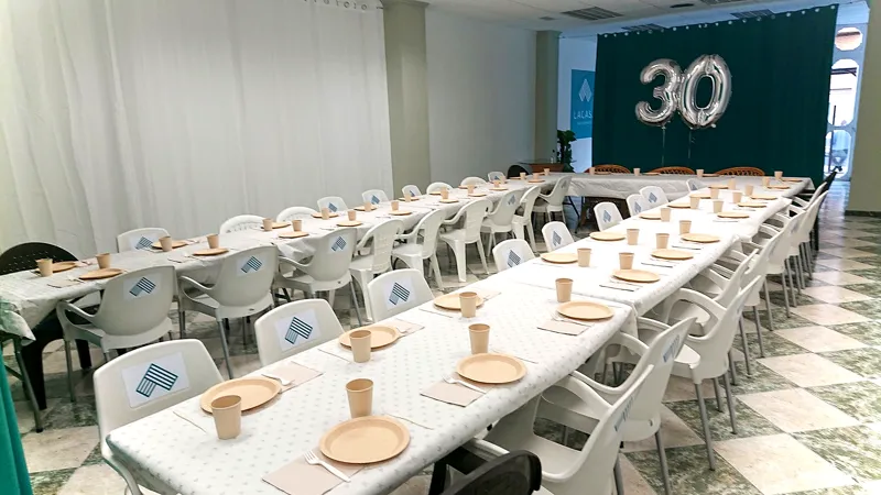 Mesa larga con mantel blanco y globos del número 30 para un cumpleaños
