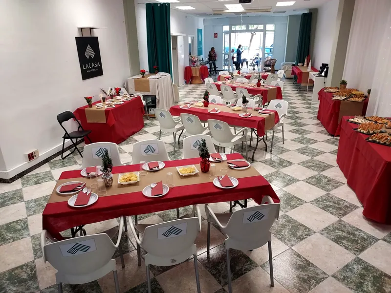 Comida de empresa con mesas de mantel rojo y sillas blancas