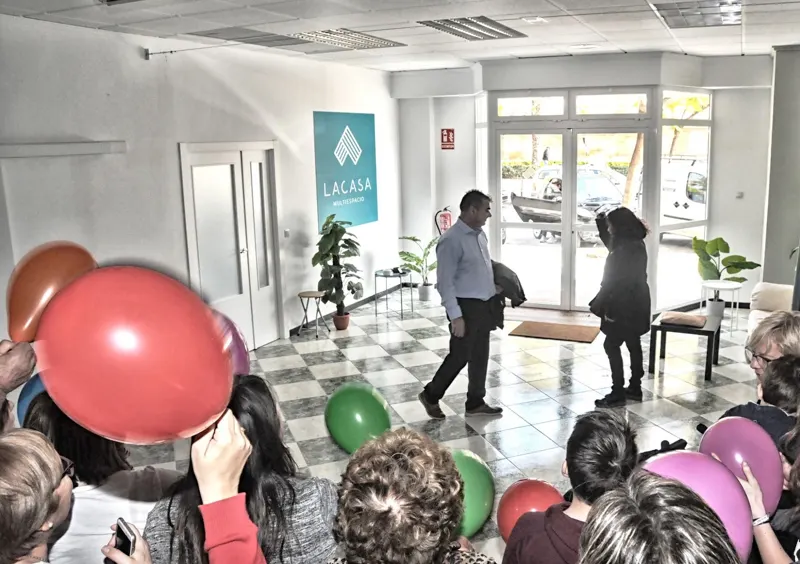 Invitados con globos llegando a una fiesta, junto a una de las entradas de la sala