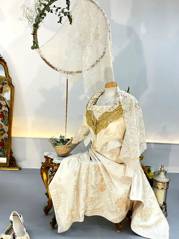 Traje de fallera con espolín dorado expuesto en un maniquí junto a un espejo