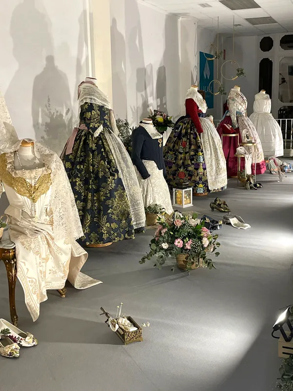 Fila de trajes de fallera expuestos en maniquíes a lo largo de la pared