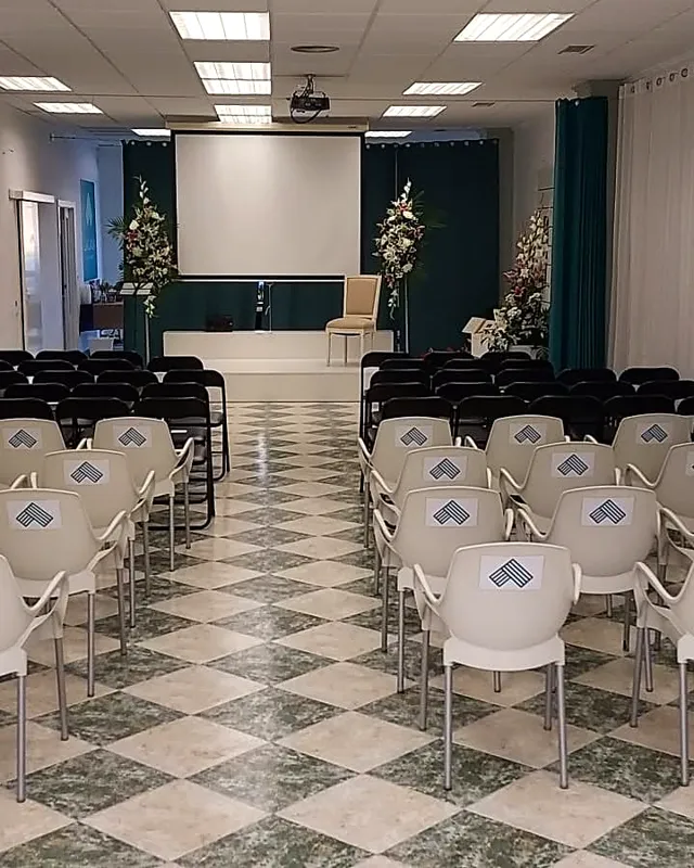 Escenario de una presentación fallera con sillón, flores y pantalla