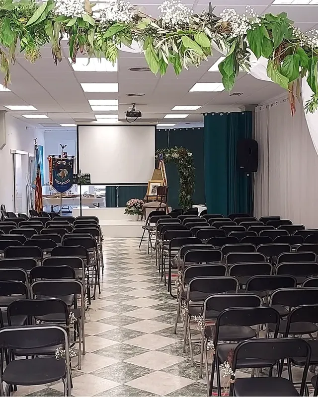 Sala montada para una presentación fallera con sillas en filas y el escenario al fondo